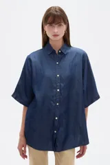 Camisa azul de jean de manga corta, corte holgado, con cuello camisero y cierre frontal con botones.