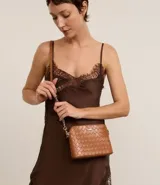 Cartera pequeña de diseño transversal con textura de efecto tressê, cierre superior con cremallera y correa larga de cadena metálica.