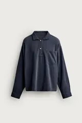 Camisa polo relaxed fit confeccionada en tejido de algodón y lino, color azul marino oscuro. Cuenta con cuello solapa, cierre frontal parcial con botones, bolsillo aplicado en el pecho y manga larga con puños abotonados.