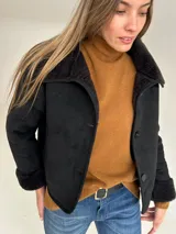 Campera tipo gamulán color negro con interior de corderito sintético, cuello solapa y cierre frontal con botones. Diseño corto y holgado.