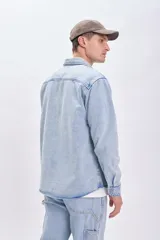 Sobrecamisa de jean celeste con cuello clásico, cierre frontal con botones metálicos, dos bolsillos de parche en el pecho y mangas largas con puños abotonados.