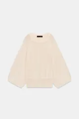 Jersey de punto color crema, con cuello redondo y mangas largas amplias tipo murciélago.
