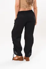 Pantalón holgado negro de lino con cintura elastizada y cordones ajustables en los laterales de las piernas.