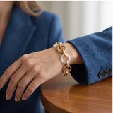 Pulsera de eslabones alternados, combinando eslabones circulares de metal dorado con eslabones circulares de cerámica blanca.