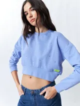 Buzo cropped negro de manga larga con apliques de brillos en el frente y puños.