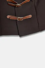 Top marrón oscuro con escote en pico, sin mangas y cierre frontal con dos trabillas de cuero marrón claro y hebillas metálicas doradas.