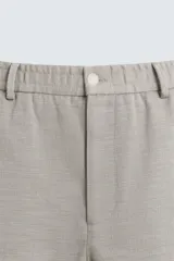 Pantalón de vestir color blanco hueso, de corte recto y tiro medio, con cintura elástica y cierre frontal de botón y cremallera. Presenta bolsillos frontales y bolsillos traseros de vivo.