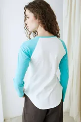 Remera de manga larga estilo raglan, color verde militar, con cuello redondo y dobladillo inferior curvado.