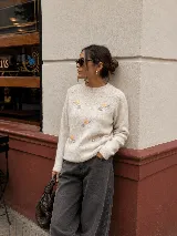Sweater de punto color crema con cuello redondo y mangas largas, decorado con un delicado bordado de flores pequeñas en tonos amarillos, celestes y grises.