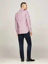 Camisa de corte slim confeccionada en algodón Oxford con textura dobby. Presenta cuello con botones, puños redondeados y el logo de Tommy Hilfiger bordado en el pecho.