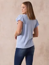 Blusa celeste en tejido pointelle con escote en V y mangas cortas con volados. Aplique de puntilla en el escote y en el frente.