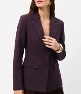Blazer entallado de color bordó, confeccionado en punto Roma con cuello de solapa, manga larga, cierre frontal de dos botones y bolsillos con tapa.