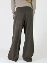 Pantalon de vestir de corte sastrero y tiro alto, con pinzas frontales, cierre de doble botón y pernera ancha.