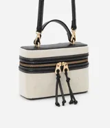 Cartera pequeña tipo bandolera de la marca Satinato, color beige con detalles en negro, confeccionada en una mezcla de algodón y poliuretano con forro de poliéster. Cuenta con tapa con doble cierre, cordón decorativo, asa de mano y correa larga removible.