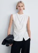 Blusa blanca sin mangas con cuello redondo y diseño cruzado con drapeado lateral.
