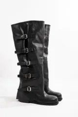 Botas altas de cuero negro con caña alta y múltiples correas con hebillas plateadas.