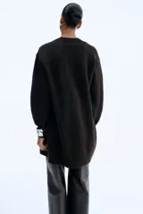 Saco largo de punto fino color marrón oscuro, con hombros caídos, ribete acanalado en nuca, puños y bajo. Sin cierre.