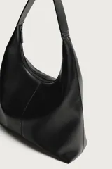 Bolso tipo shopper color negro con diseño liso, asa de hombro y compartimento principal con cierre de cremallera.