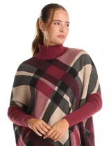 Polera estilo poncho de corte oversize, con cuello alto tejido y mangas largas con puños elásticos. Presenta un diseño de estampado a cuadros en tonos bordó, beige y negro.