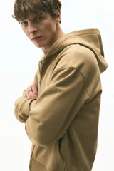 Campera con capucha de corte boxy confeccionada en felpa de algodón pesado. Presenta cierre frontal completo, bolsillos tipo canguro, capucha forrada y terminaciones acanaladas en puños y ruedo.