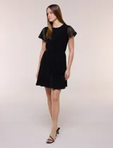 Vestido corto de seda fría elastizada negra, con mangas cortas de encaje calado, lazo ajustable en la cintura y ruedo con volado.