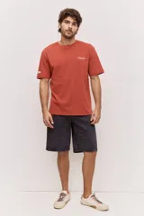 Remera blanca de algodón, de corte holgado y mangas cortas, con pequeño estampado azul en el pecho.