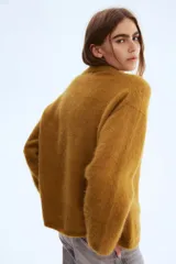 Buzo oversized de punto suave en color mostaza, confeccionado en mezcla de lana y mohair. Presenta un diseño de hombros caídos con cuello redondo, puños y bajo acanalados.