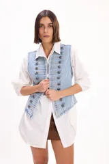 Chaleco de denim color azul claro, sin mangas, con diseño estilo militar decorado con doble botonadura metálica frontal.