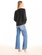 Blusa negra de gasa, marca Tahari, con escote en V y detalle de punto smock en los hombros. Manga larga con terminación plisada y puños elásticos.