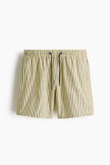 Short de baño de sirsaca color amarillo con rayas verticales oscuras, cintura elástica con cordón de ajuste y bolsillos laterales.