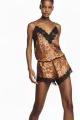 Musculosa de mujer confeccionada en georgette devoré, con escote en V y delicados detalles de encaje negro. Silueta liviana y fluida de color ocre con estampado paisley.