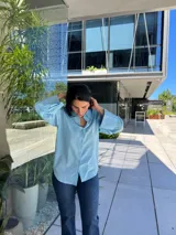 Camisa celeste de manga larga con puños anchos, cuello clásico y cierre frontal abotonado.