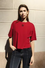 Remera de algodón color rojo intenso, con corte boxy y cuello redondo. Presenta un pequeño logo bordado en color negro en el pecho.