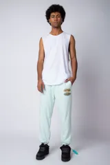 Pantalón jogger de corte oversize confeccionado en tela rústica color verde agua claro. Presenta una estampa gráfica localizada en el muslo izquierdo con diseño de óvalos y estrellas.