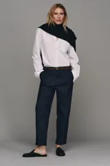 Pantalón chino de tiro bajo color marrón oscuro, con pernera recta y bajo con vuelta. Incluye un cinturón trenzado delgado de color marrón claro. Cuenta con bolsillos delanteros y cierre frontal con cremallera y botón.