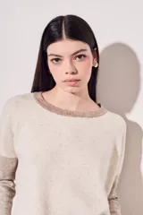 Sweater de punto color beige con mangas marrones y cuello y ruedo en azul marino.