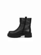 Bota corta de cuero sintético color negro, con suela track dentada y detalle de hebilla metálica en el lateral superior.