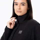 Buzo polar de mujer con cuello alto y cierre frontal parcial con botones a presión. Presenta un diseño de manga larga con puños elásticos y un parche con logo en el pecho.
