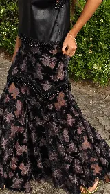 Falda larga de encaje de terciopelo color negro, con diseño en capas y detalle de galón de piedras en la cadera.