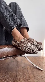 Mocasines náuticos de cuero con pelo natural con estampado animal print tipo vaca, cordones decorativos en el empeine y suela flexible.