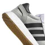 Championes Adidas modelo I-5923, con diseño de inspiración retro en color gris claro con las icónicas tres rayas laterales en negro. Presenta una entresuela con tecnología Boost para mayor amortiguación y suela de goma color caramelo.