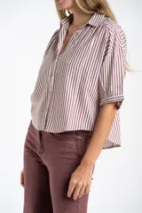 Camisa de corte oversize con estampado de rayas verticales, cuello clásico y mangas cortas. Presenta cierre frontal con botones y un diseño fluido y ligero.
