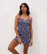 Pijama short doll de dos piezas en color azul marino con estampa integral de Hello Kitty en tono claro. Consta de una musculosa de tirantes finos con escote en V decorado con un pequeño lazo y un short con cintura elástica.