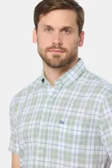 Camisa de manga corta con cuello abotonado y estampado a cuadros en tonos verde claro, blanco y azul. Corte slim fit y bolsillo en el pecho.