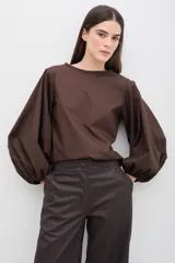 Blusa color marrón chocolate con mangas abullonadas de gran volumen y diseño estructurado.