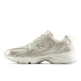 Championes urbanos New Balance modelo 530, color beige y dorado, confeccionados con malla transpirable y superposiciones de cuero sintético. Cuentan con entresuela ABZORB para mayor amortiguación y diseño retro de running.
