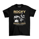 Remera negra de algodón con estampa frontal cinematográfica que representa la pelea entre Rocky Balboa y Apollo Creed, con tipografía en color dorado.