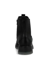 Botín tipo Chelsea de cuero negro con laterales elásticos, diseño de caña media y suela robusta de poliuretano con base gris traslúcida.