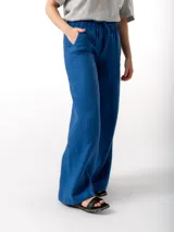 Pantalón de lino azul con corte amplio, cintura elastizada con cordón ajustable, dos bolsillos laterales y un bolsillo trasero.