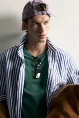 Camisa relaxed fit confeccionada en tejido de algodón, con diseño de rayas verticales en tonos azul y blanco, cuello con botones y manga larga.